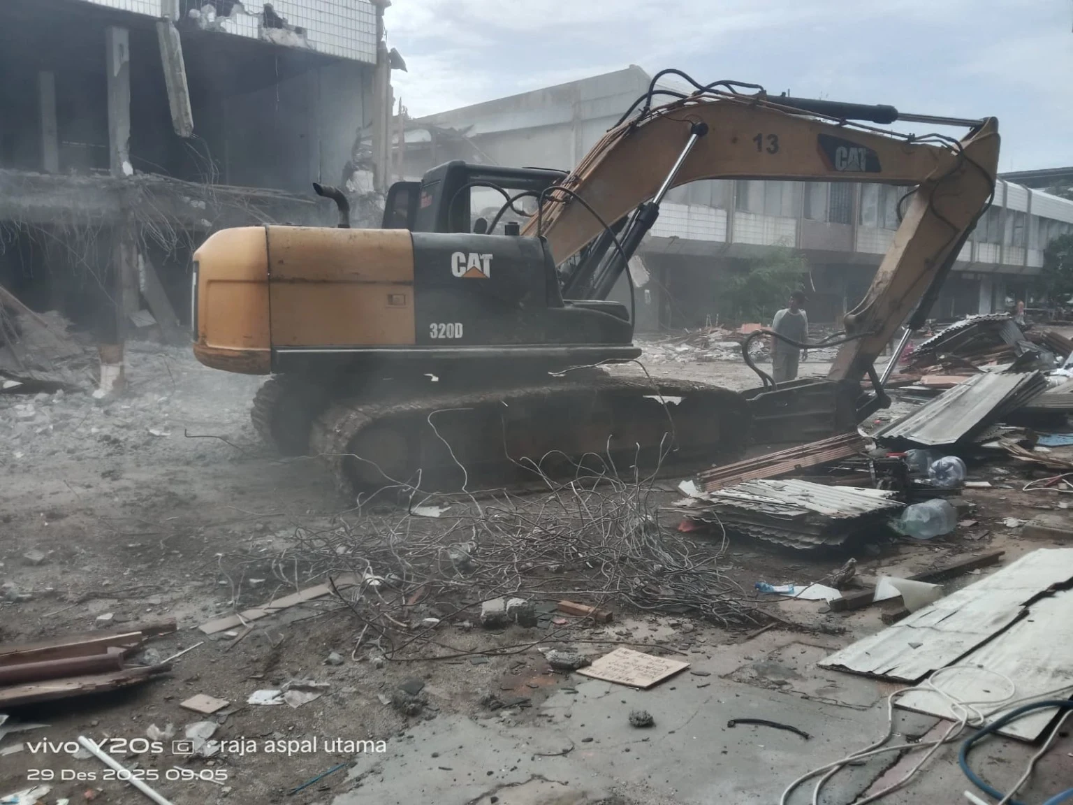 Excavator CAT 320D menangani puing pembongkaran bangunan lama