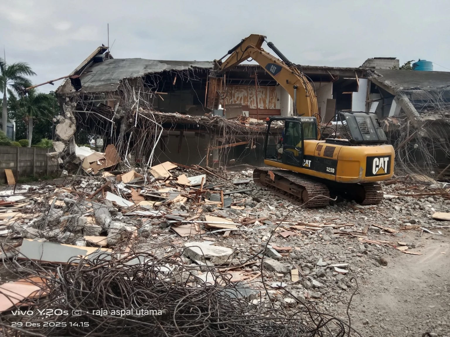 Excavator membongkar struktur rumah tua di antara puing bangunan