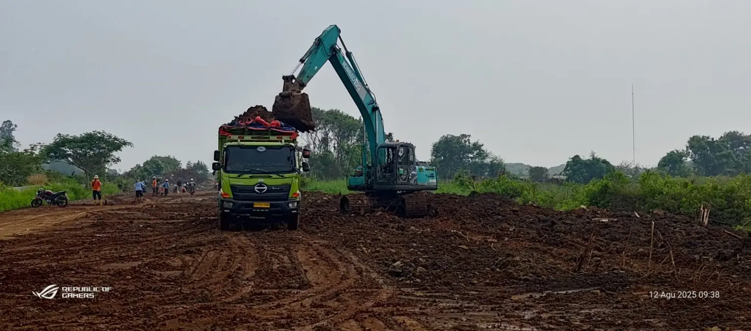 Excavator memuat material tanah ke dump truck pada pekerjaan land clearing
